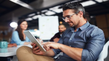 A man uses his iPad in an office. 